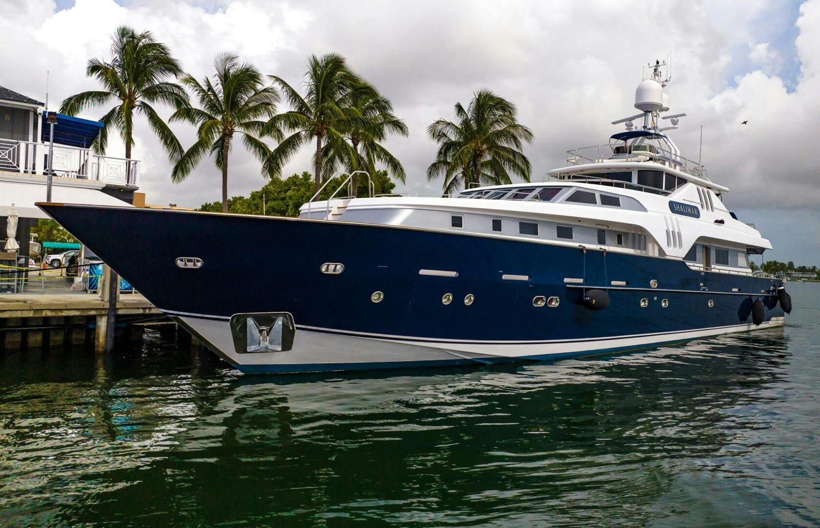 a large white boat docked at a dock aboard SHALIMAR Yacht for Sale
