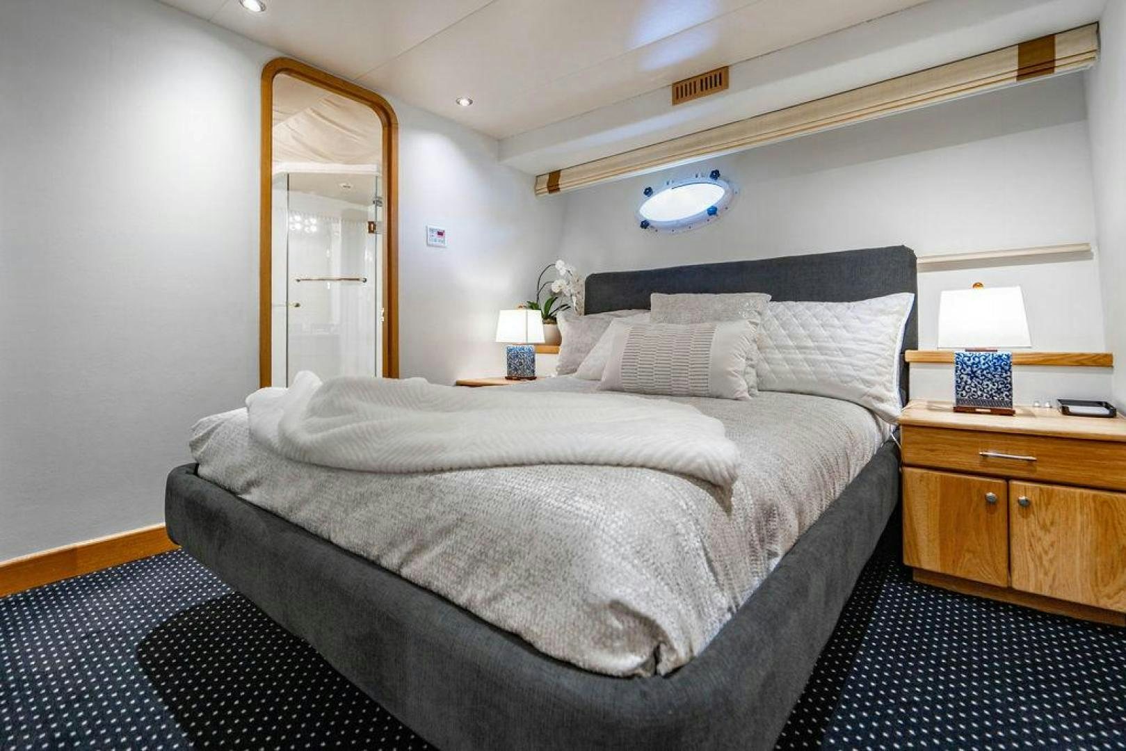 a bed with a black and white comforter and a blue rug aboard THREE BLESSINGS Yacht for Sale