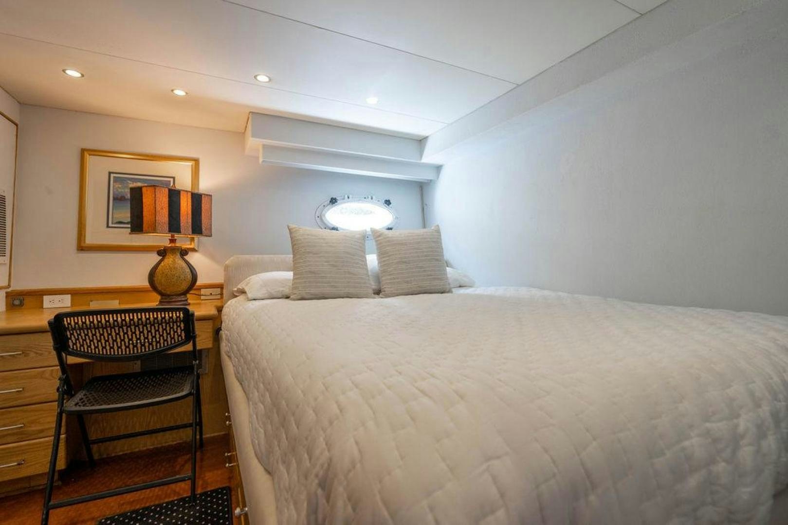 a bed with a chair and a lamp on it aboard THREE BLESSINGS Yacht for Sale