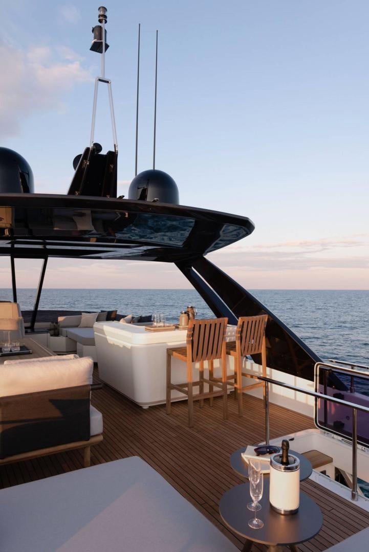 a deck with a table and chairs on it and a body of water in the background aboard ALVEARE Yacht for Sale