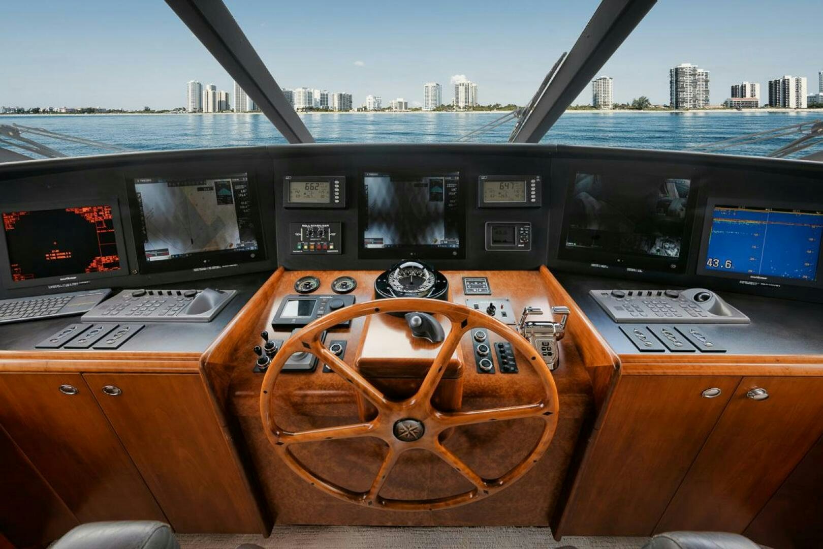 a wooden steering wheel on a wooden table with many screens aboard NATURAL 9 X KALEEN Yacht for Sale