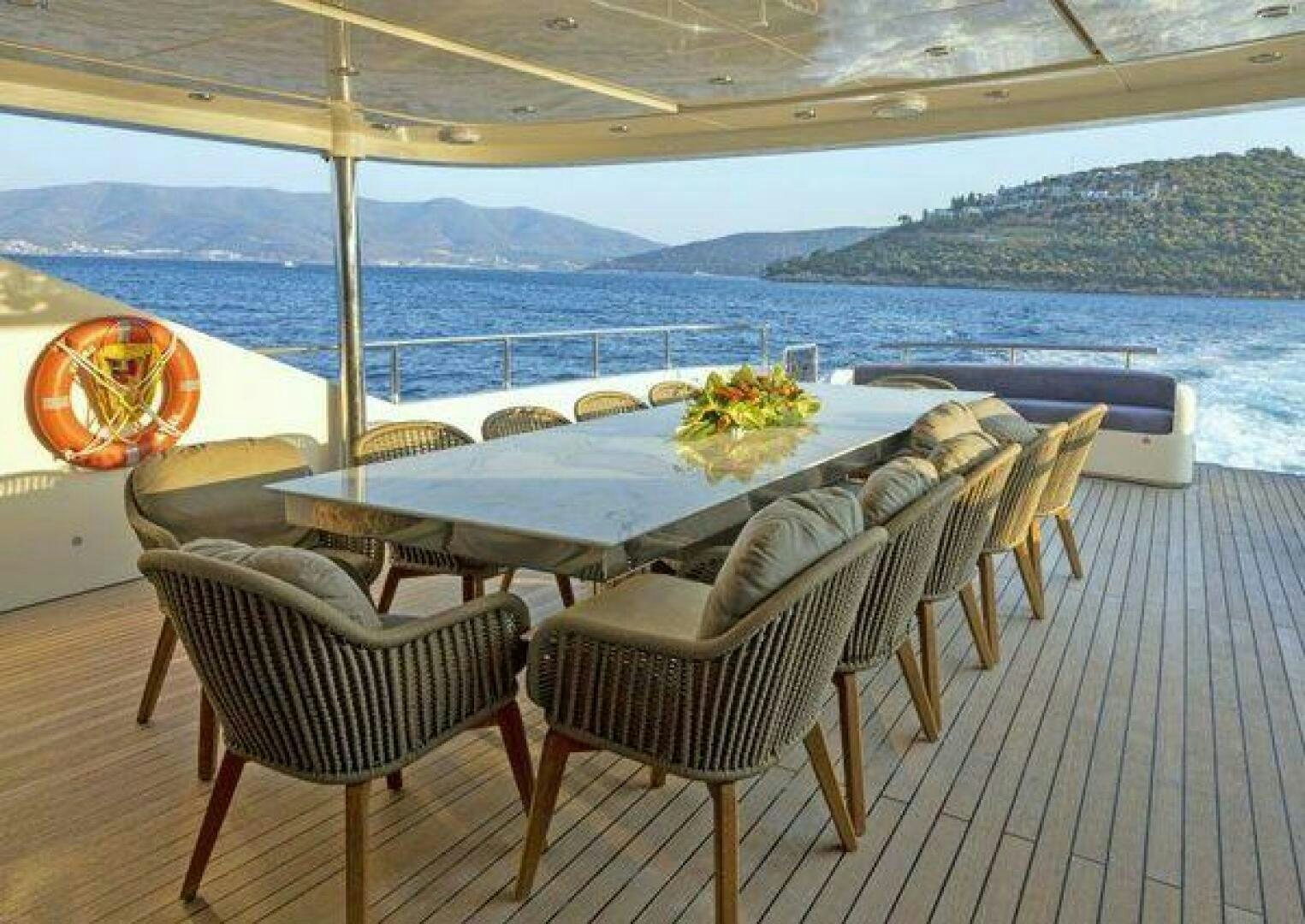 a table and chairs on a deck overlooking a body of water aboard VETRO Yacht for Sale