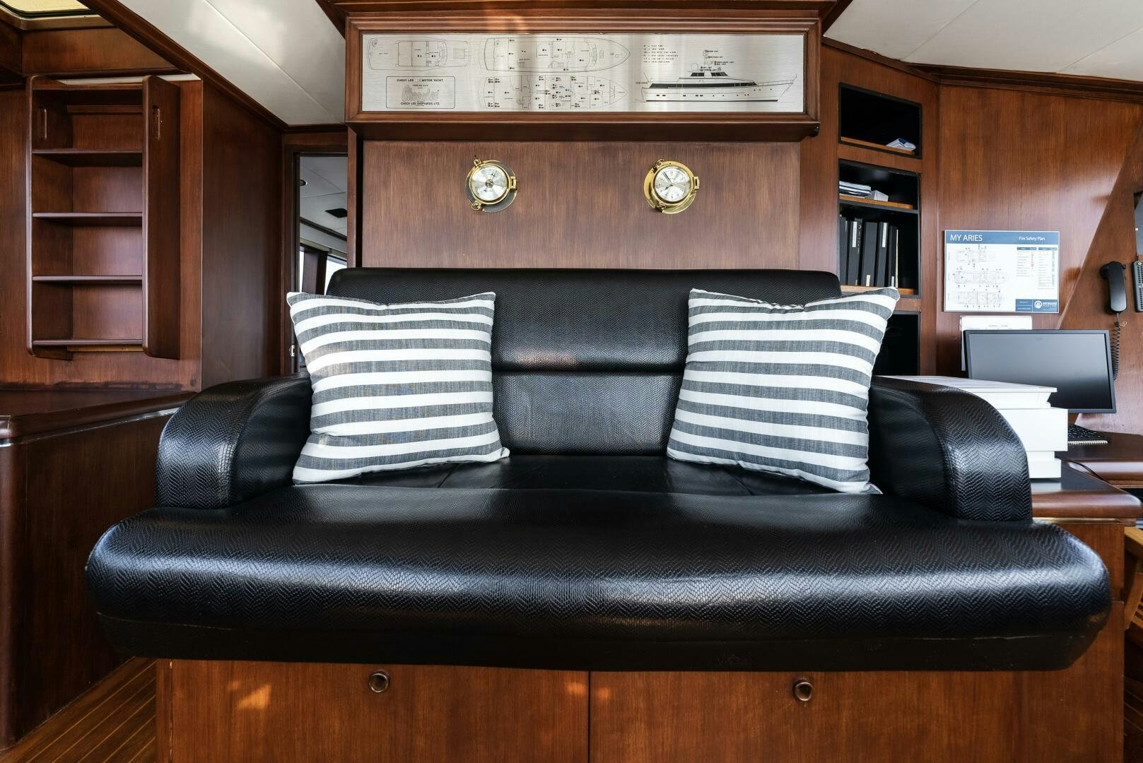 a black leather couch with white pillows aboard ARIES Yacht for Sale
