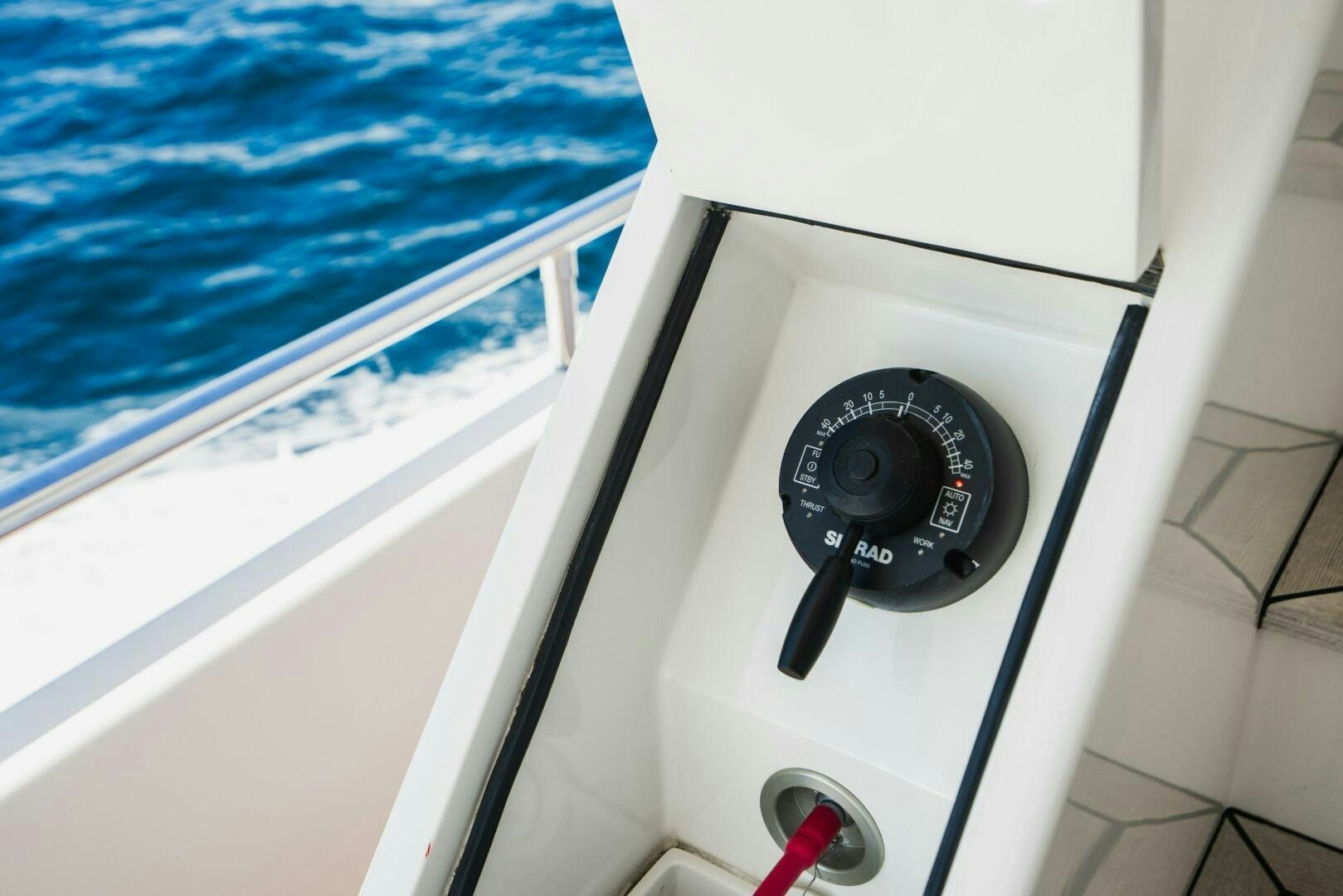 a black video game controller on a white surface next to a window aboard MOONSHOT Yacht for Sale