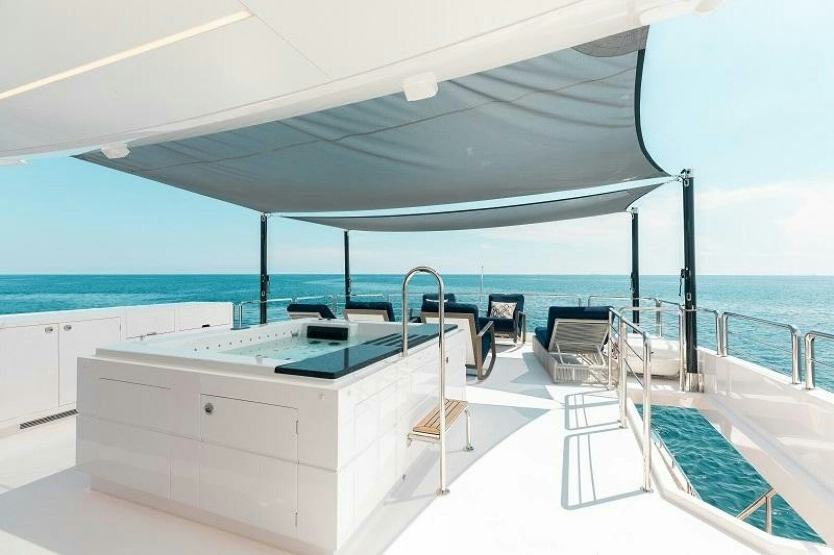 a white lounge chair on a balcony overlooking the ocean aboard WIGGLE ROOM Yacht for Sale