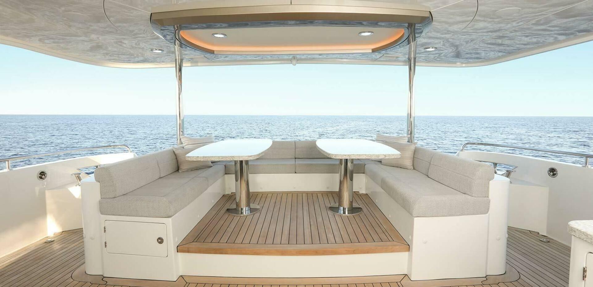 a white lounge chair next to a table and a white table on a boat aboard DRINKABILITY Yacht for Sale