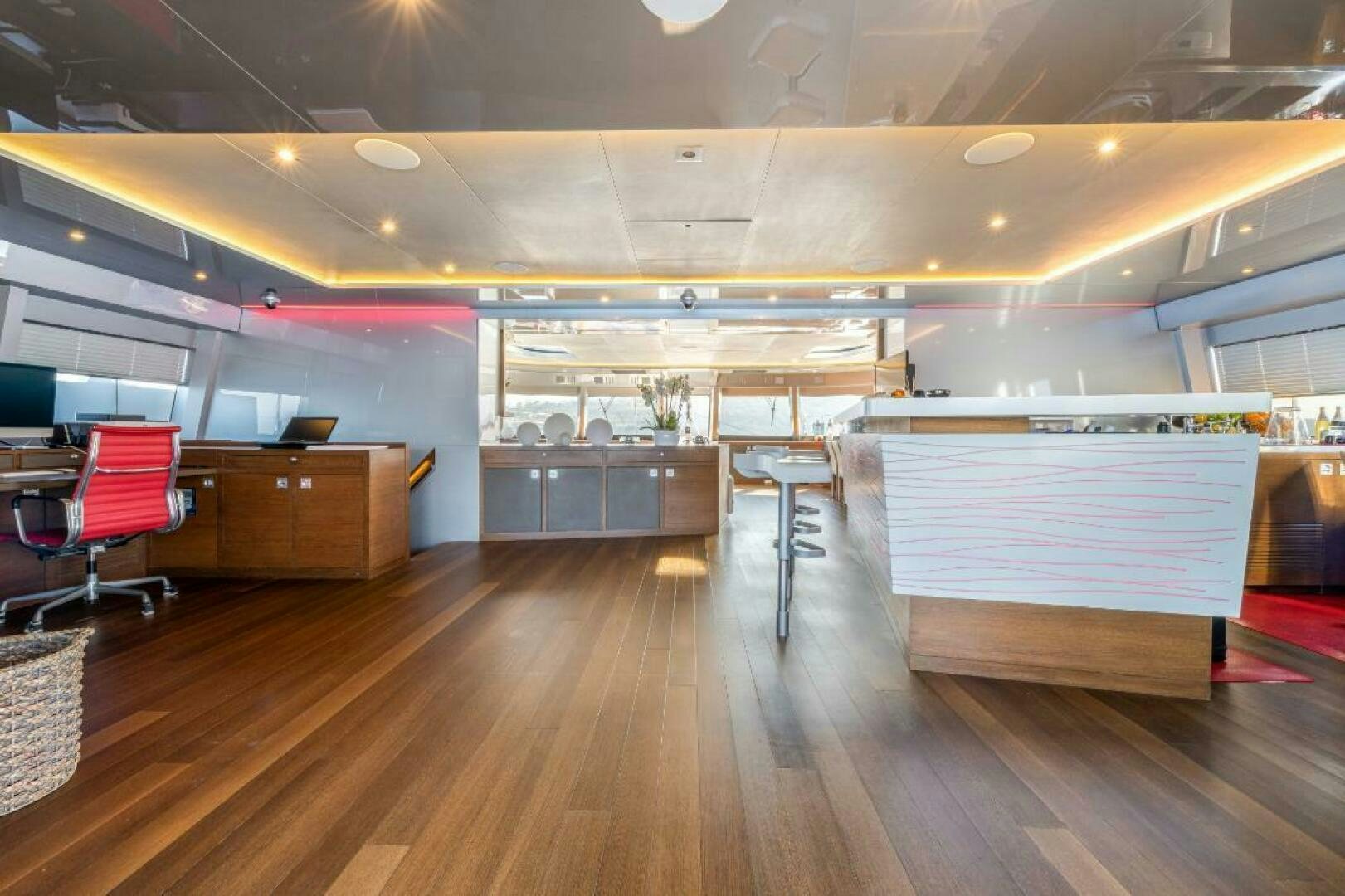 a room with a wood floor and a desk with chairs and a computer aboard MOUSETRAP Yacht for Sale