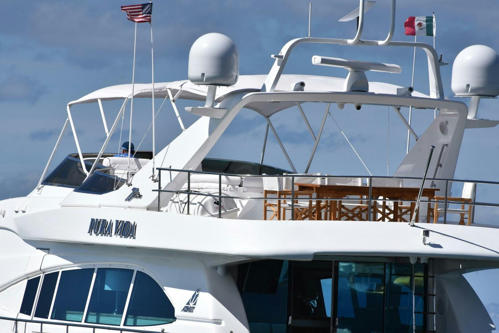 a white yacht with a flag on the front aboard PURA VIDA  Yacht for Sale