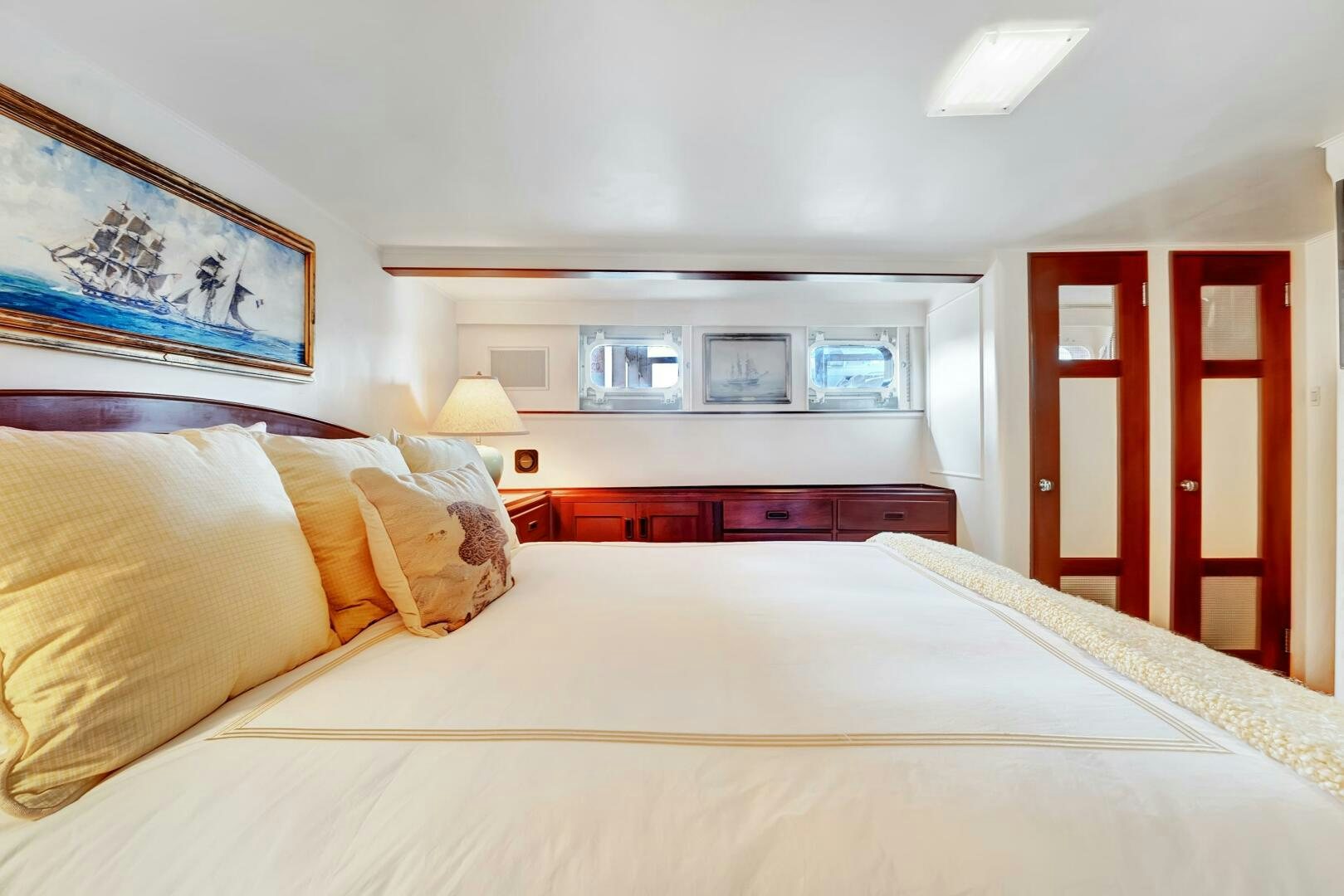 a bed with a white sheet and yellow pillows aboard EAGLE Yacht for Sale