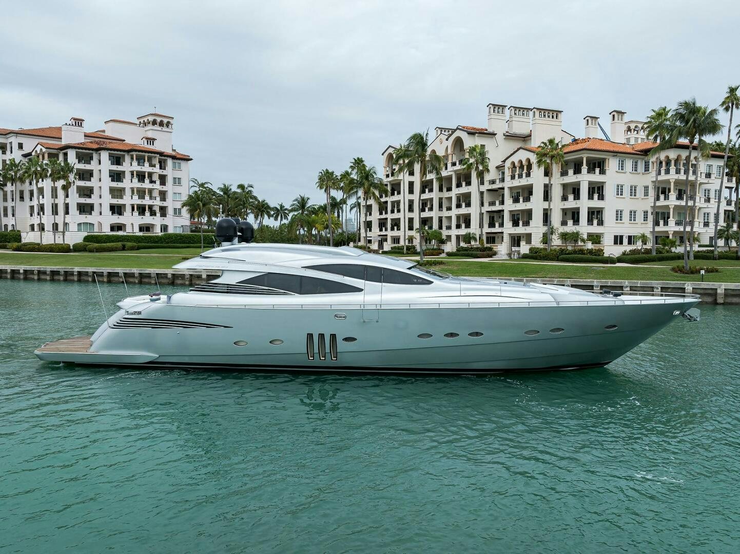 a white boat in a body of water with buildings in the background aboard MIURA Yacht for Sale