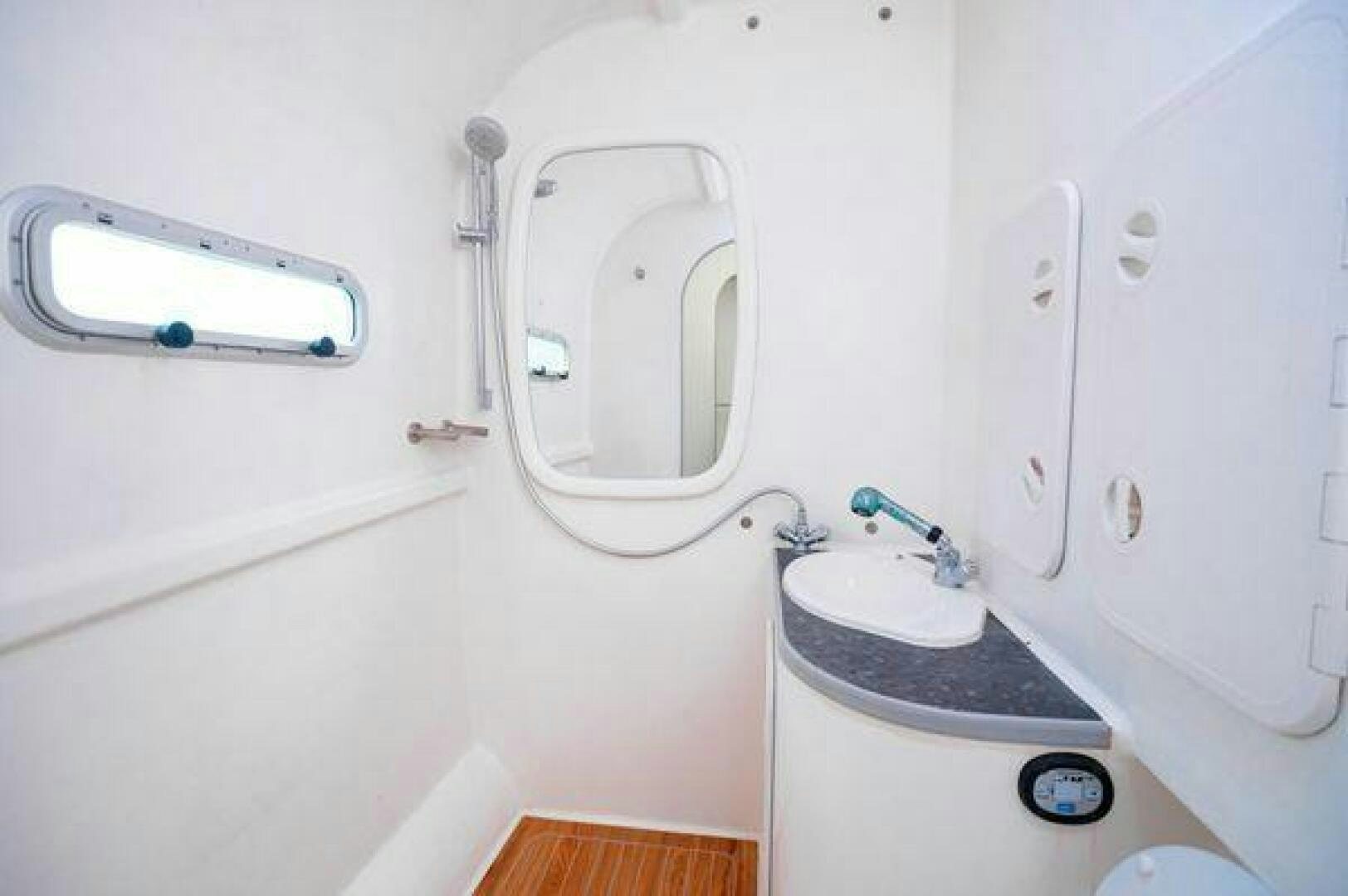 a white bathroom with a round mirror aboard SEA CHANT Yacht for Sale