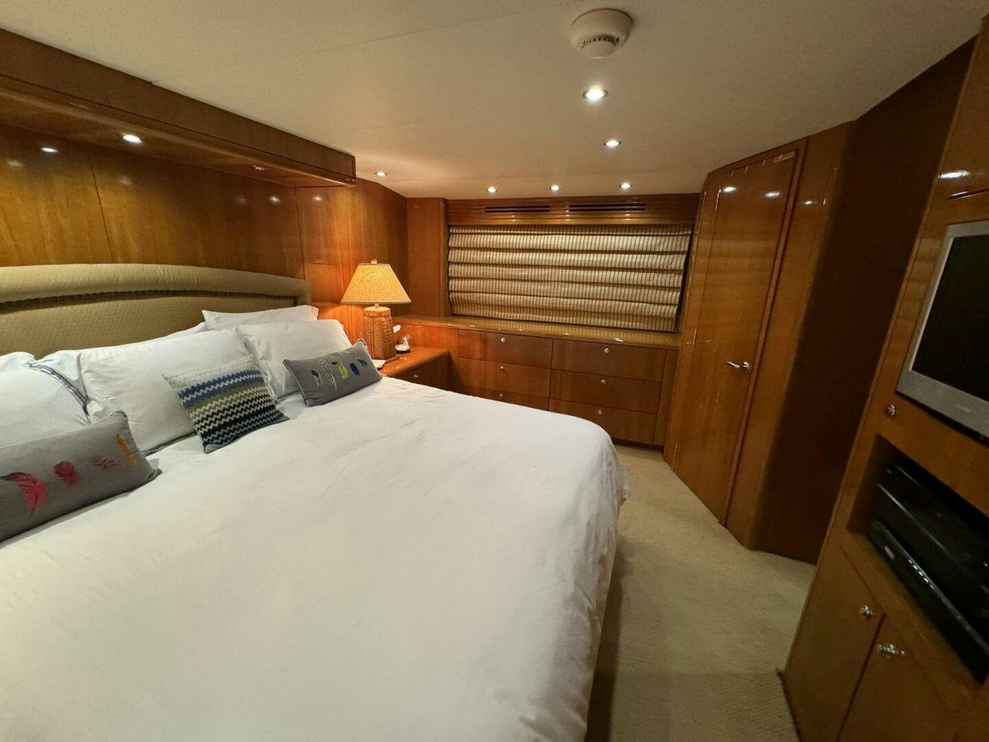 a bed with a white sheet and pillows in a room with wood walls aboard MRS. Z Yacht for Sale