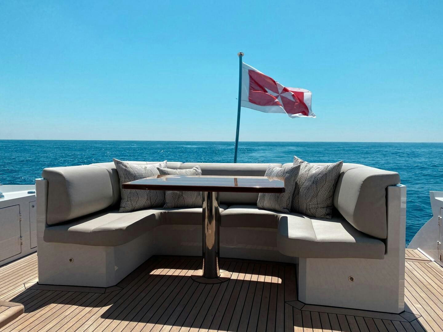 a white couch with a flag on it by a body of water aboard JUST THE TWO OF US Yacht for Sale