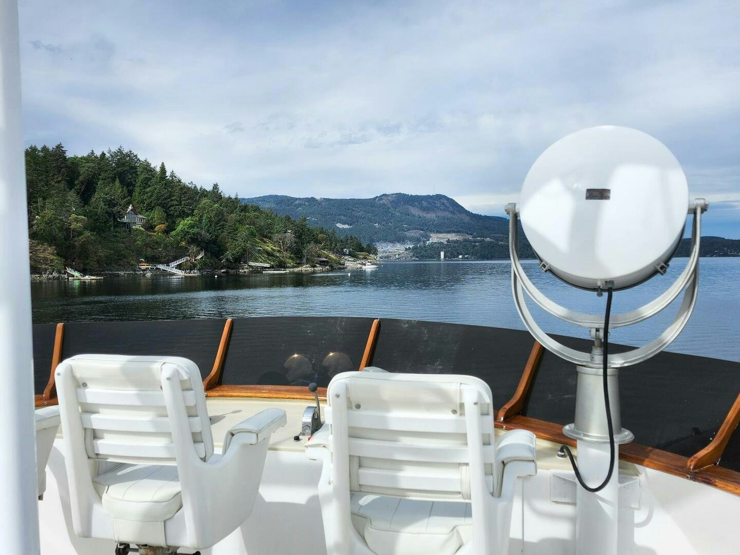 a deck with chairs and a body of water and trees in the background aboard PIONEER Yacht for Sale