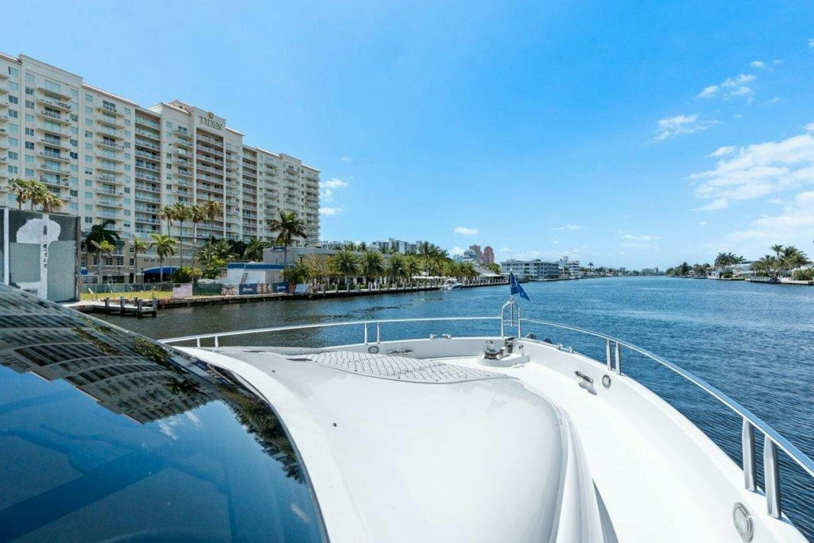 a large white boat on a body of water with buildings in the background aboard FOMO2 Yacht for Sale