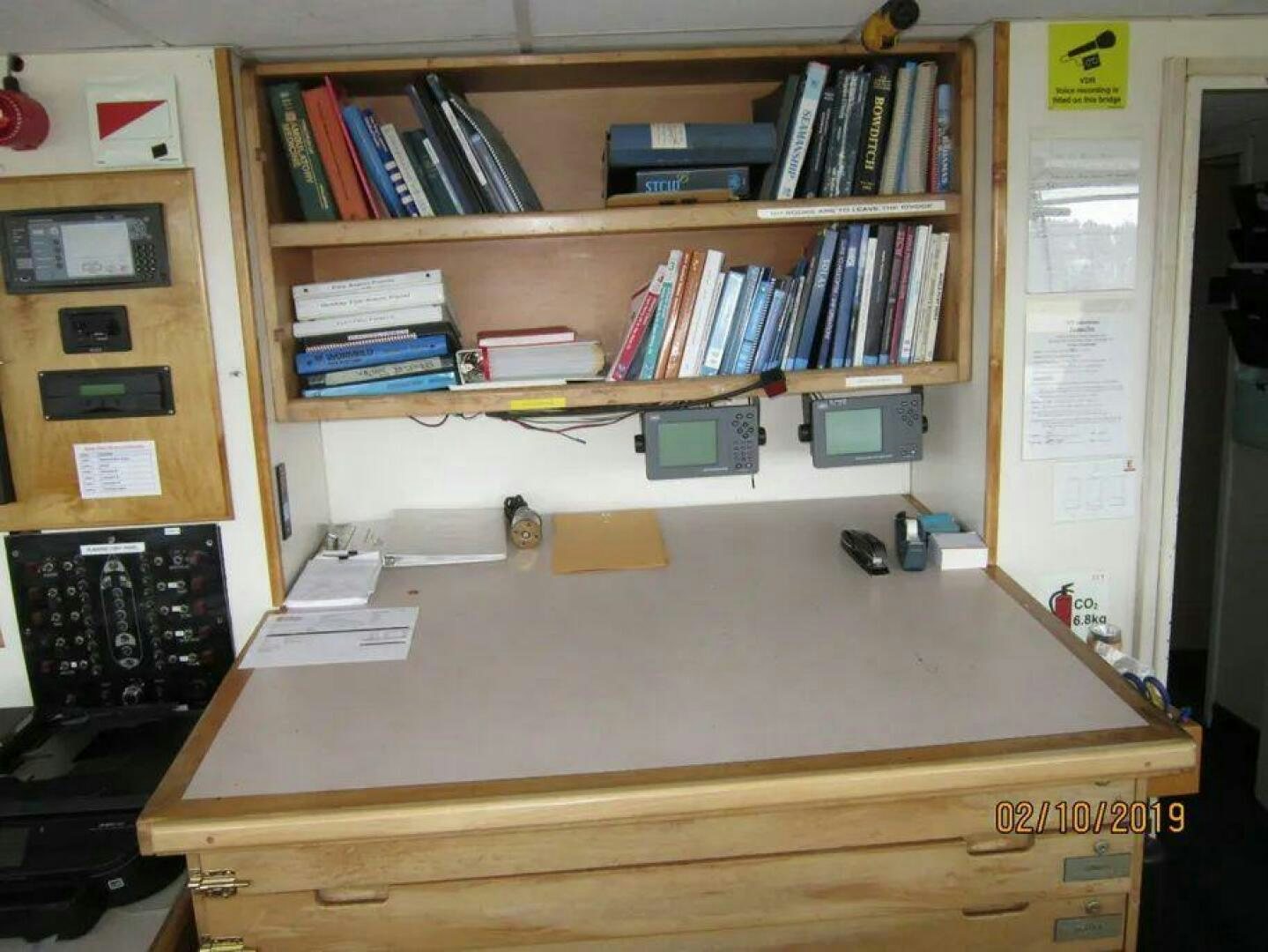 a desk with a computer and books on it aboard AMERICANA Yacht for Sale
