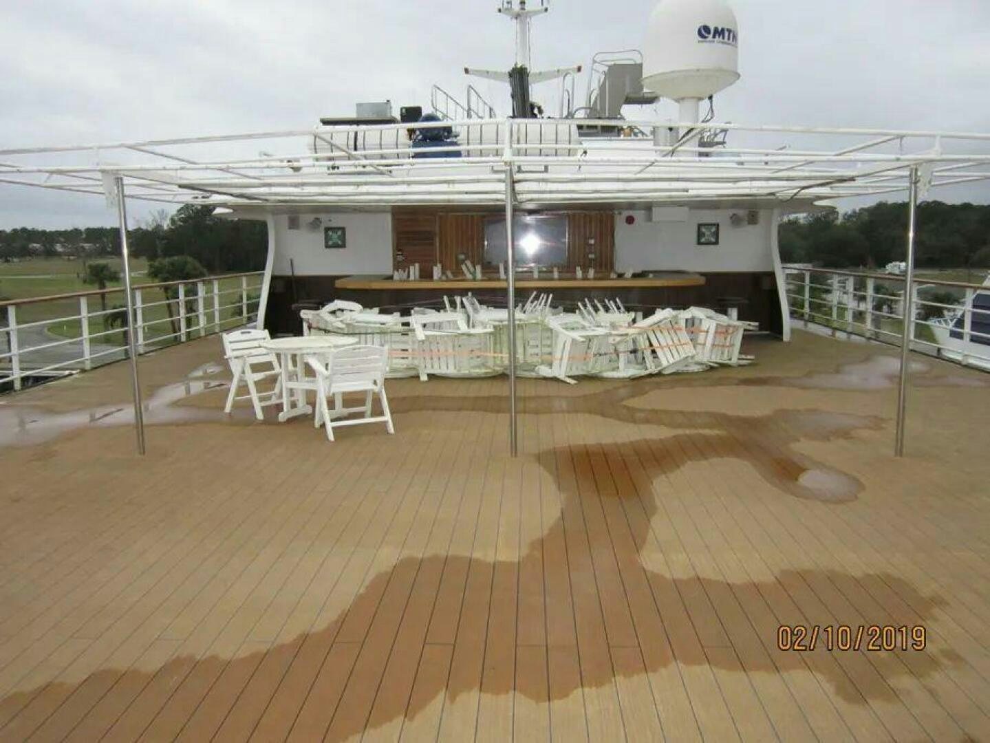 a deck with tables and chairs aboard AMERICANA Yacht for Sale