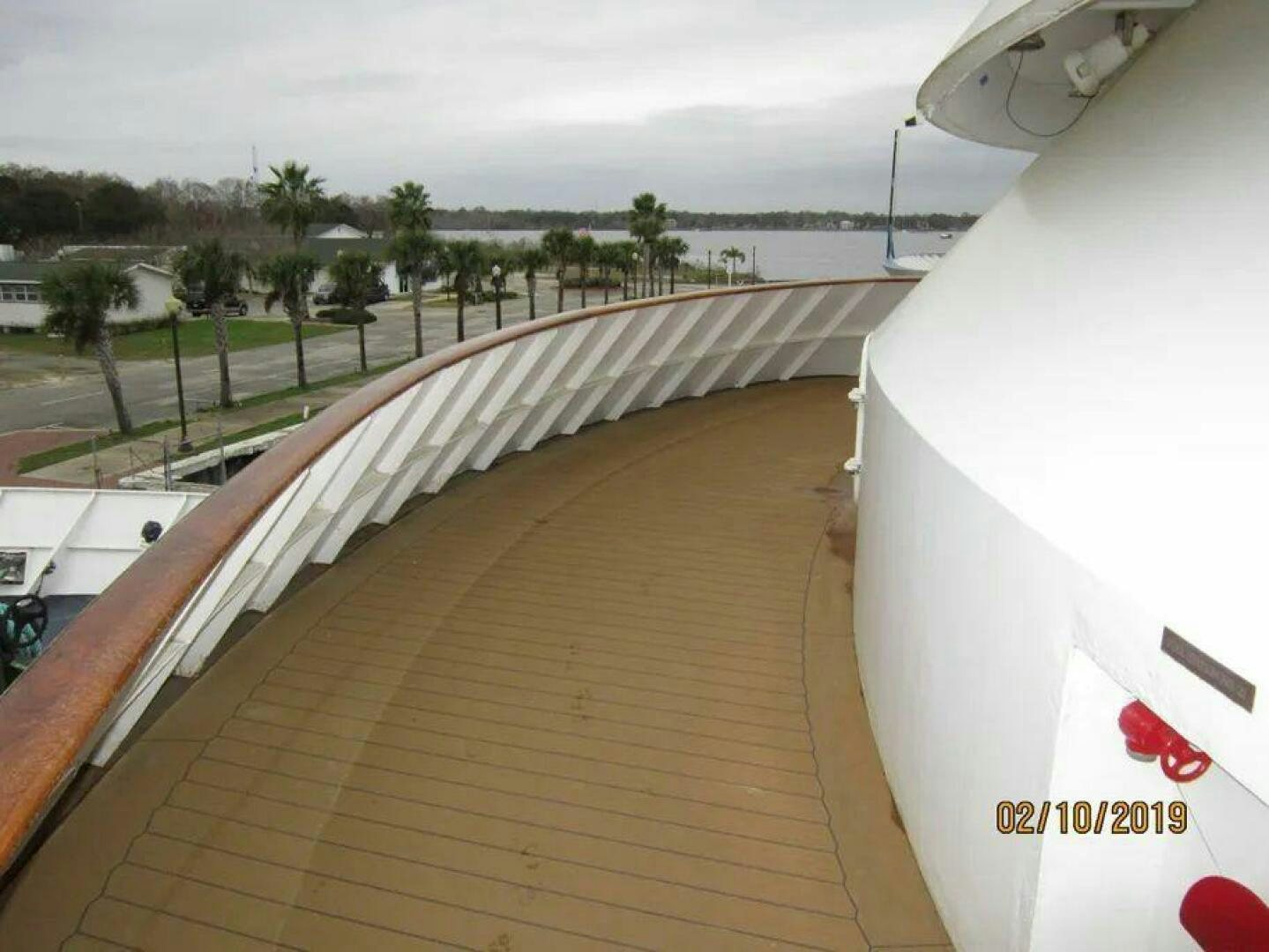 a deck with a railing and trees aboard AMERICANA Yacht for Sale