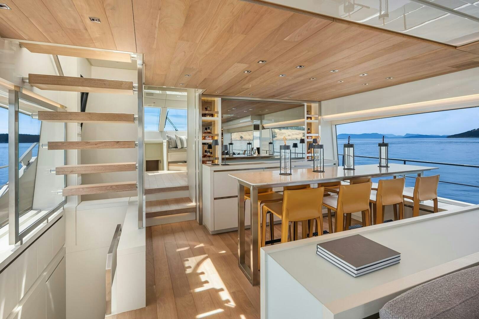 a wood table with chairs and a large window with a wood railing aboard SANLORENZO SL86 Yacht for Sale