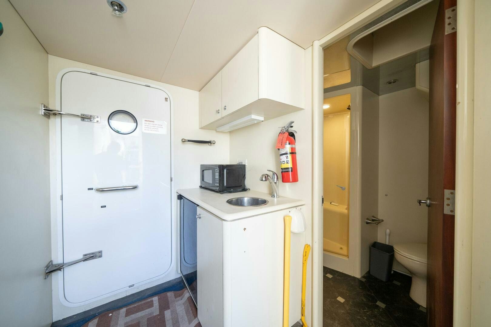 a small kitchen with a white refrigerator aboard E Yacht for Sale