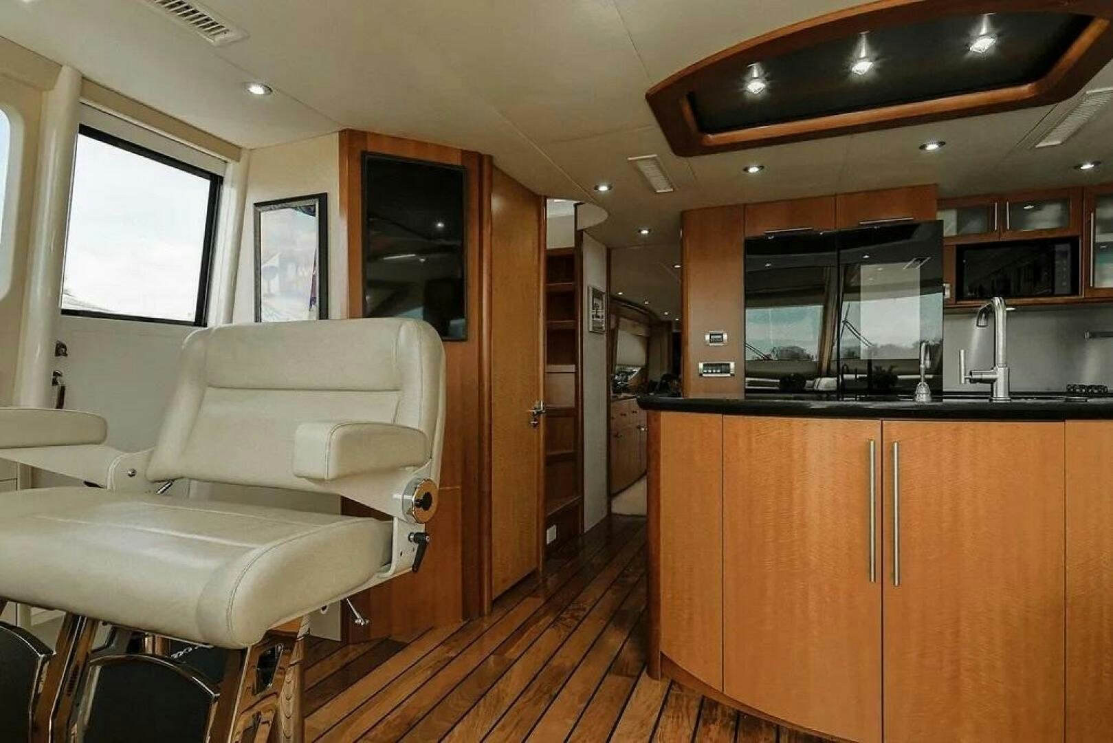 a room with a wood floor and a kitchen with a wood cabinet aboard CERCA TROVA Yacht for Sale