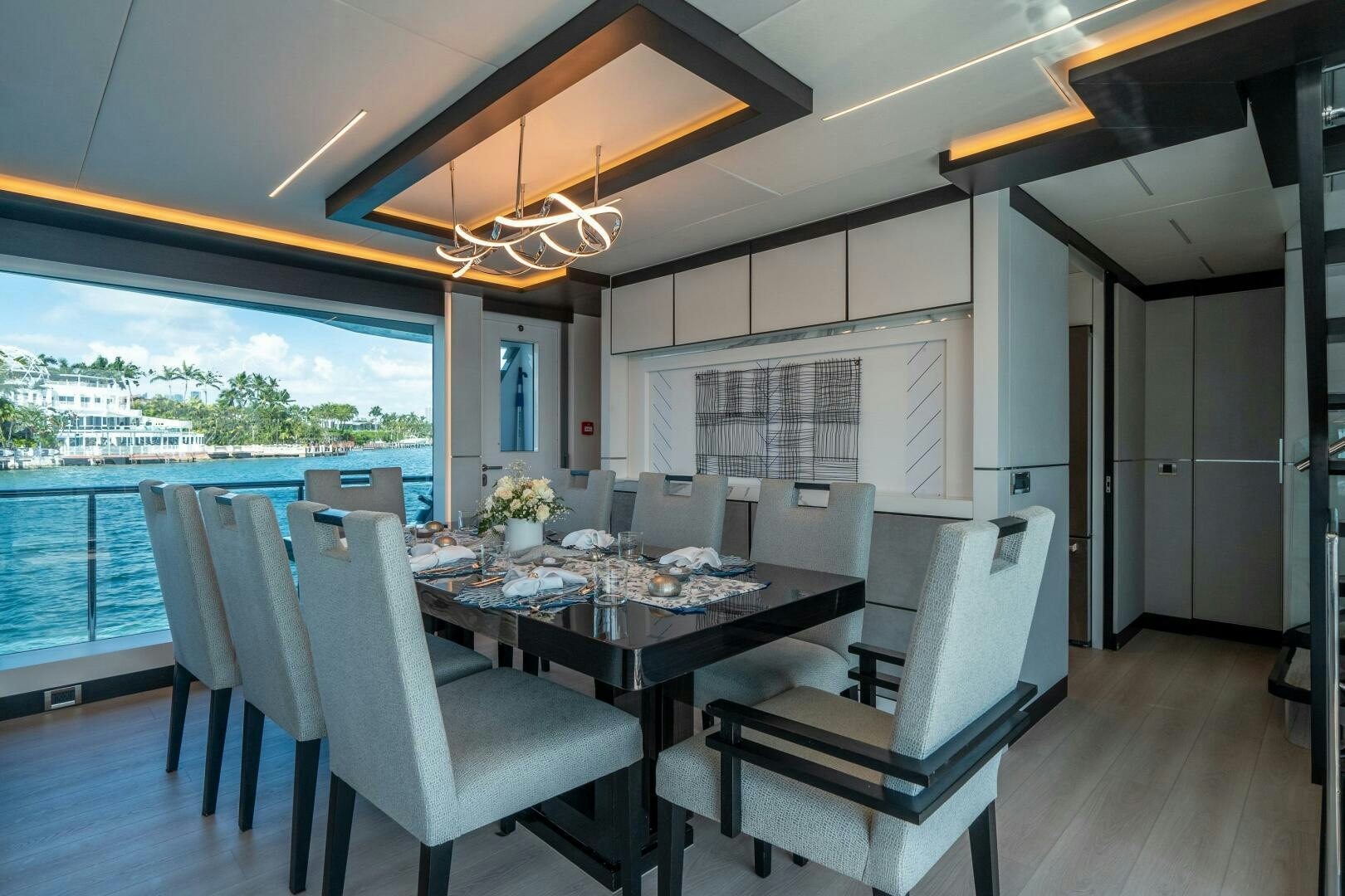 a dining table and chairs in a room with a view of the city aboard DAY ONE Yacht for Sale