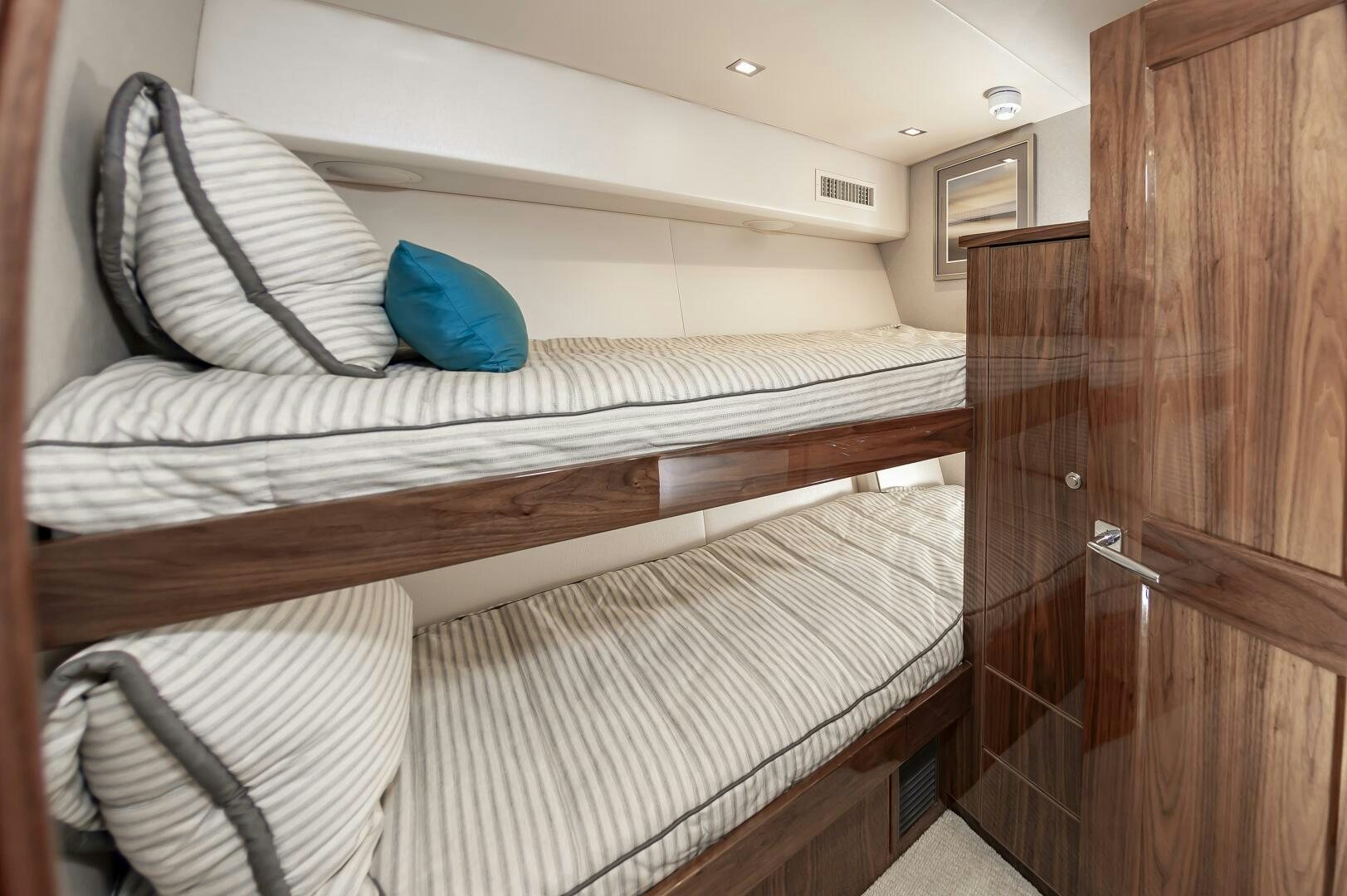 a bed with a white sheet and a blue pillow on it aboard MERCENARIA Yacht for Sale