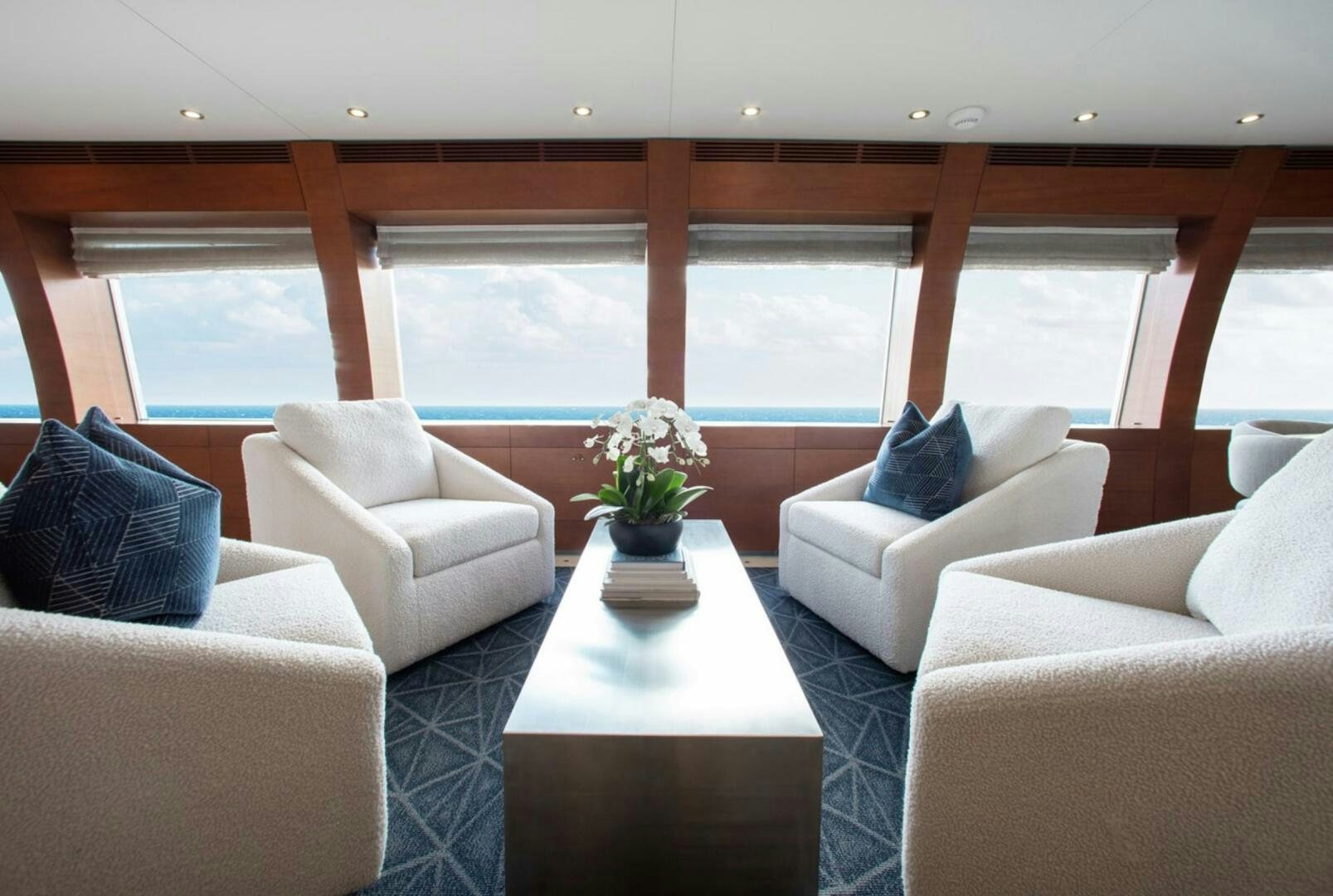 a room with white couches and a table with a plant in it aboard MATRIX Yacht for Sale