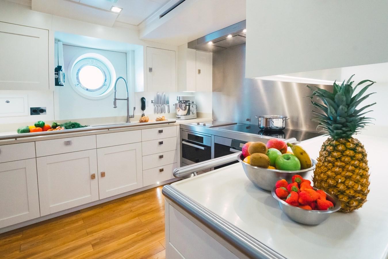 a kitchen with white cabinets and a bowl of fruit on the counter aboard MIKHAIL S. VORONTSOV Yacht for Sale