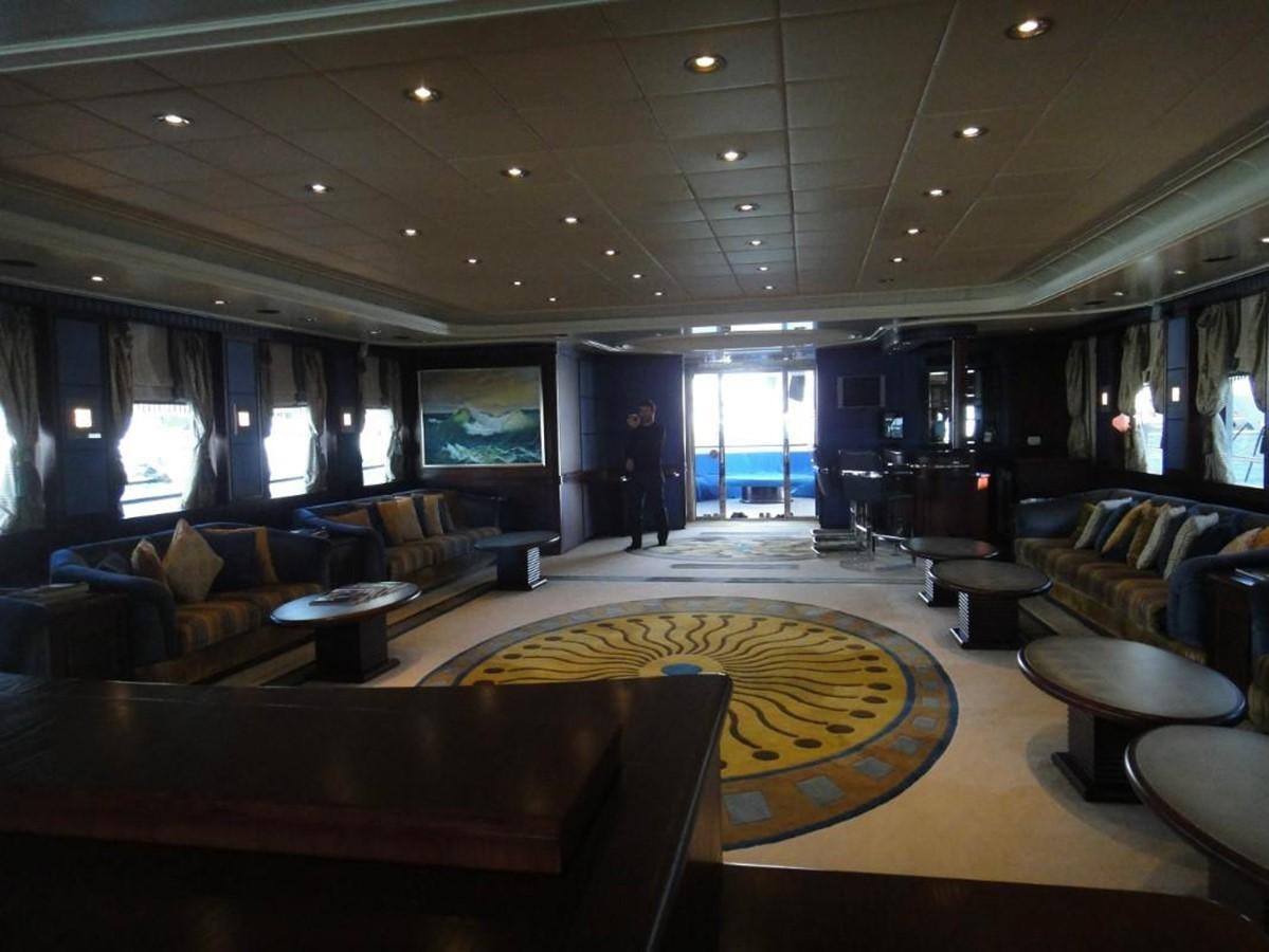 a large room with leather couches and a yellow rug aboard WARSAN Yacht for Sale