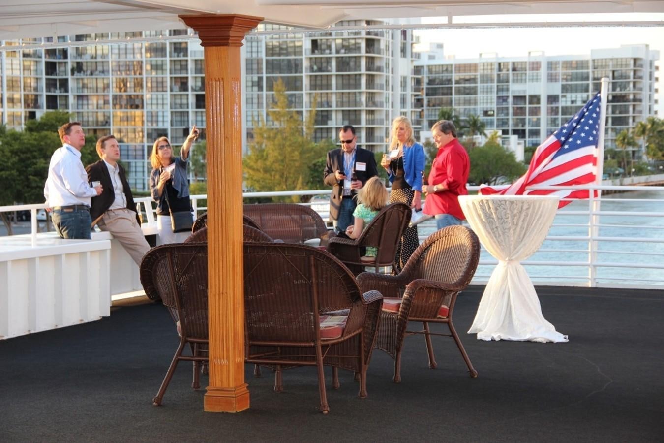 a group of people standing around a table with a flag on it aboard SIR WINSTON Yacht for Sale