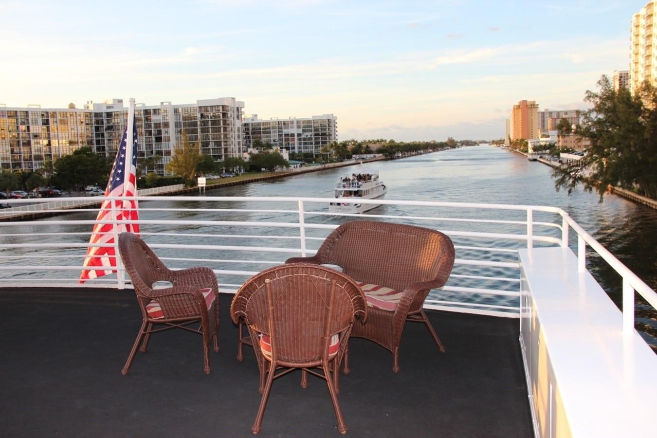 a couple of chairs on a balcony overlooking a river and a boat aboard SIR WINSTON Yacht for Sale