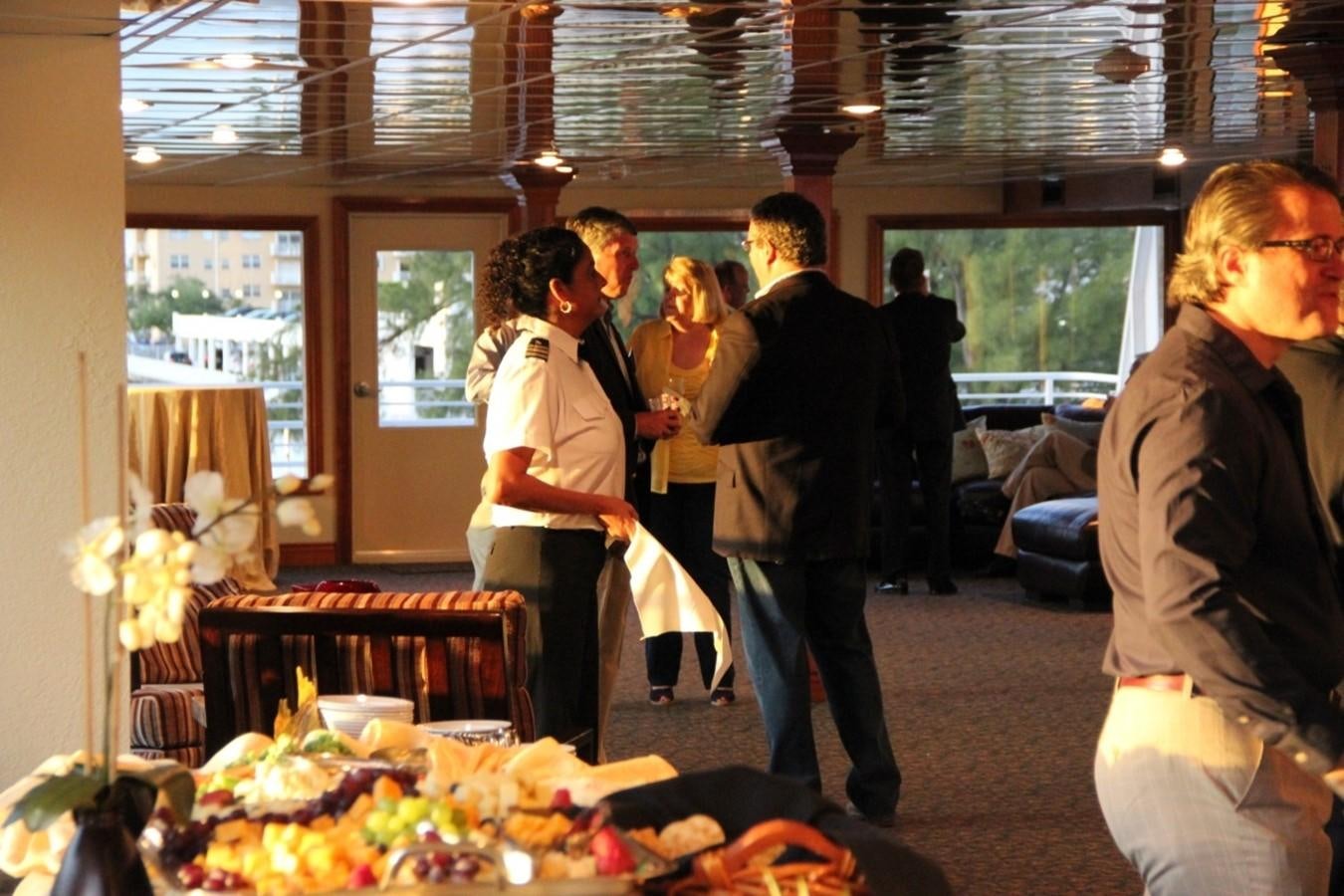 a group of people standing in a room with flowers and tables aboard SIR WINSTON Yacht for Sale