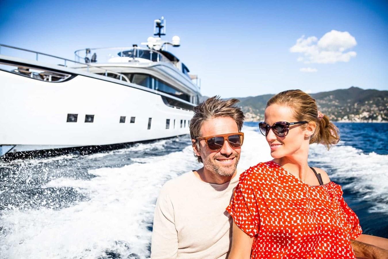 a man and woman posing for a picture in front of a boat aboard GTT 130 Yacht for Sale