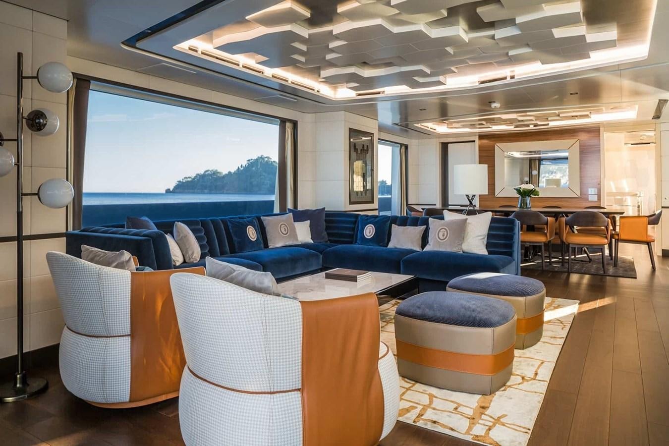 a living room with a large blue couch and a large window aboard GTT 130 Yacht for Sale