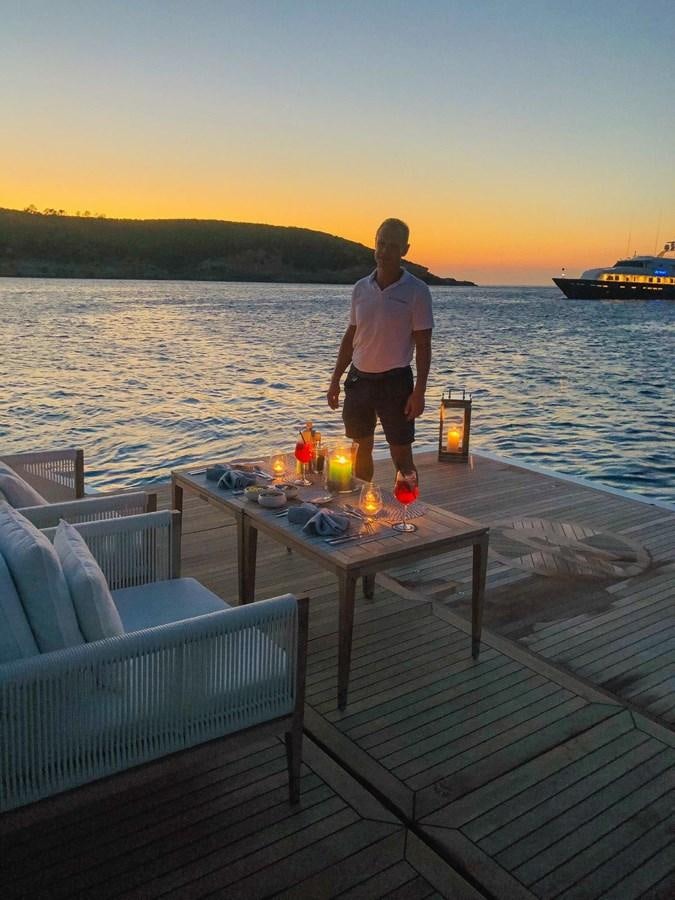 a man standing on a deck overlooking a body of water aboard GTT 130 Yacht for Sale