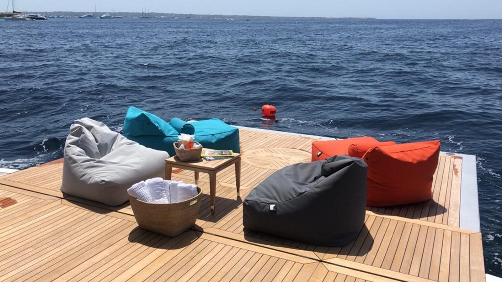 a deck with a table and chairs on it by the water aboard GTT 130 Yacht for Sale
