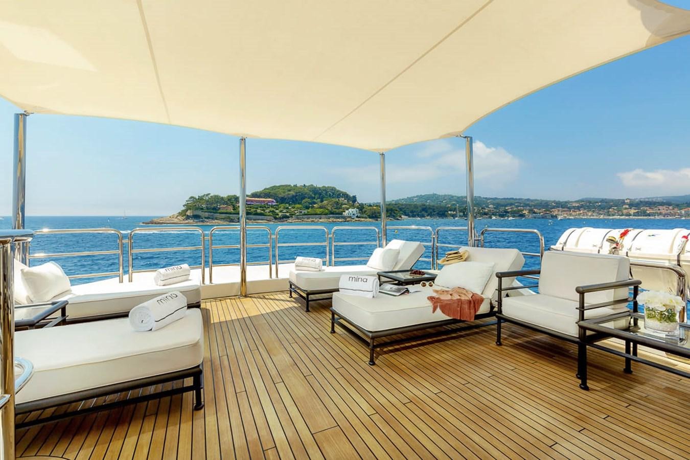 a deck with a view of the ocean and a couple of beds aboard MINA Yacht for Sale