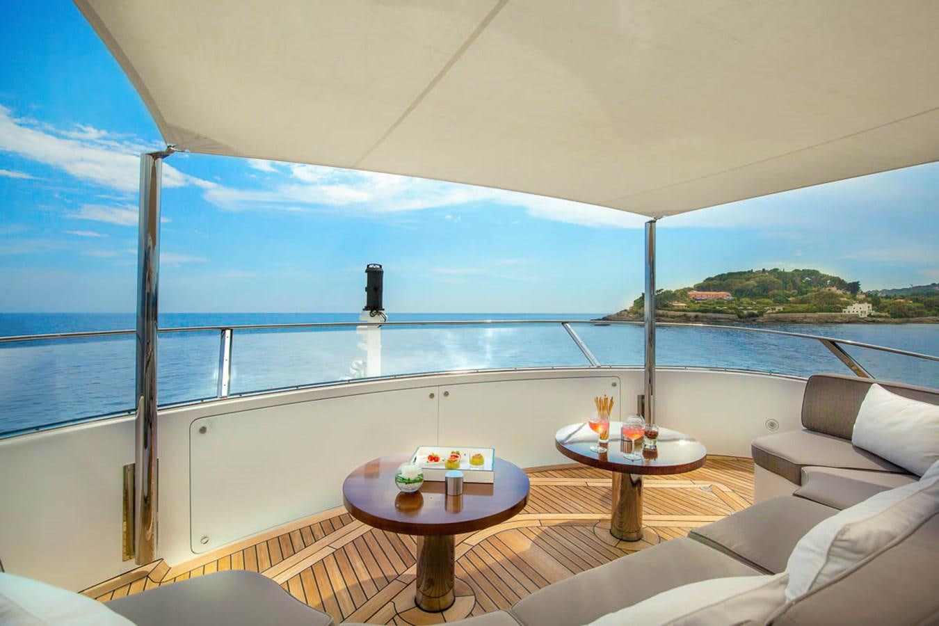 a table and a couch on a balcony overlooking a body of water aboard MINA Yacht for Sale
