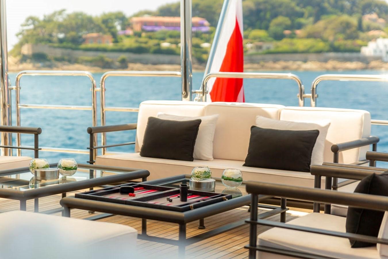 a table with a red umbrella on it next to a white couch aboard MINA Yacht for Sale