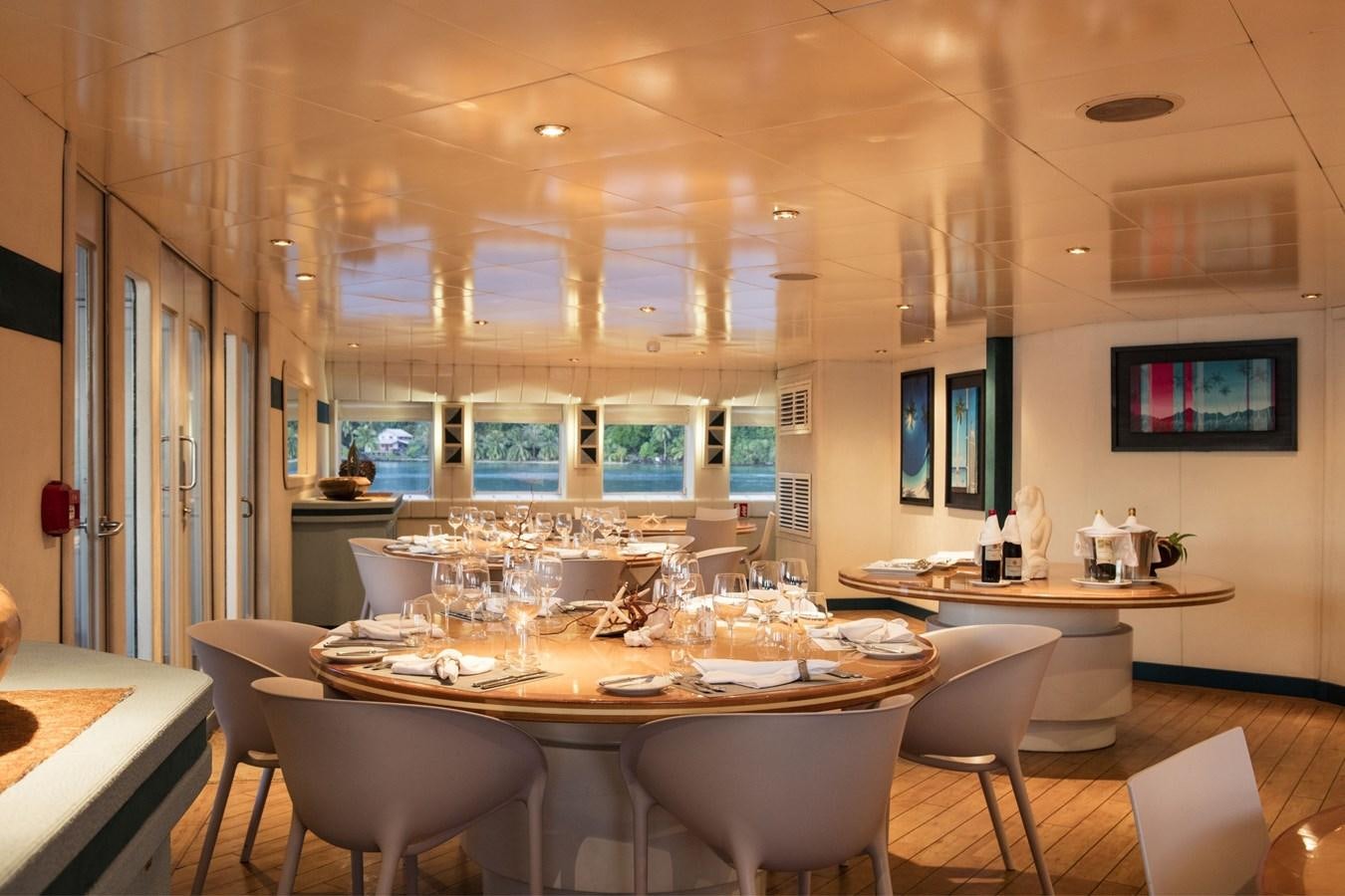 a room with tables and chairs aboard HAUMANA Yacht for Sale