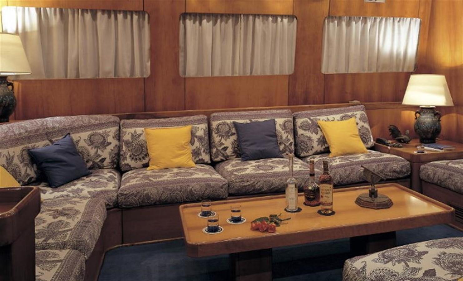 a living room with a couch and a table with bottles and a lamp aboard BARCABLU Yacht for Sale