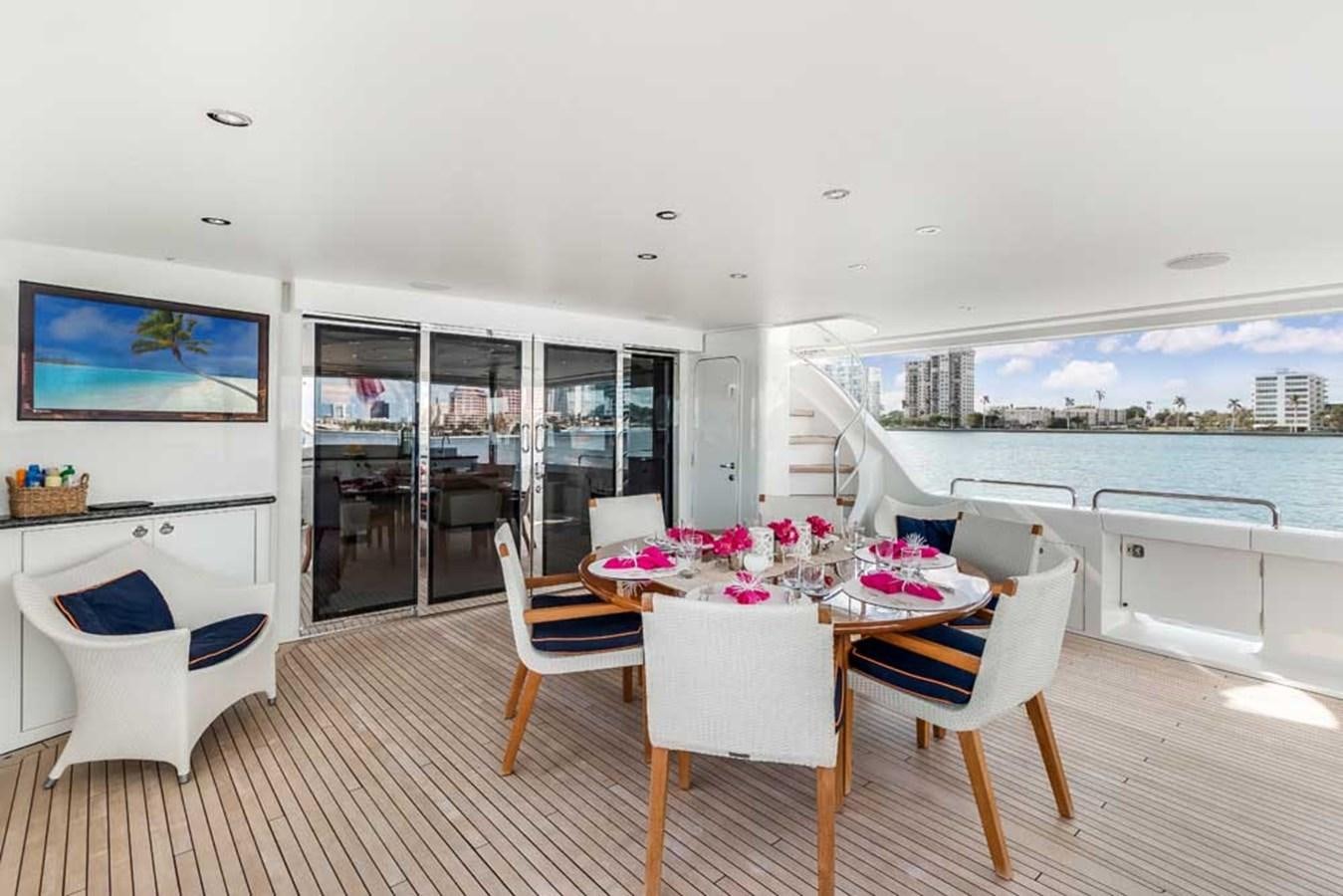 a dining table and chairs on a deck overlooking a body of water aboard OUR HERITAGE Yacht for Sale