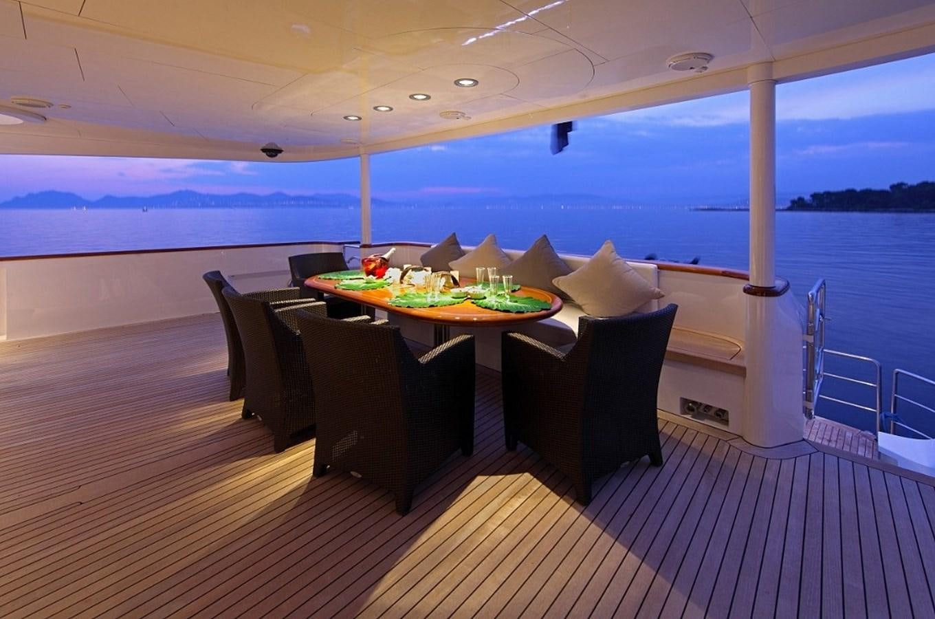 a table with chairs and a large body of water in the background aboard SEA SHELL Yacht for Sale