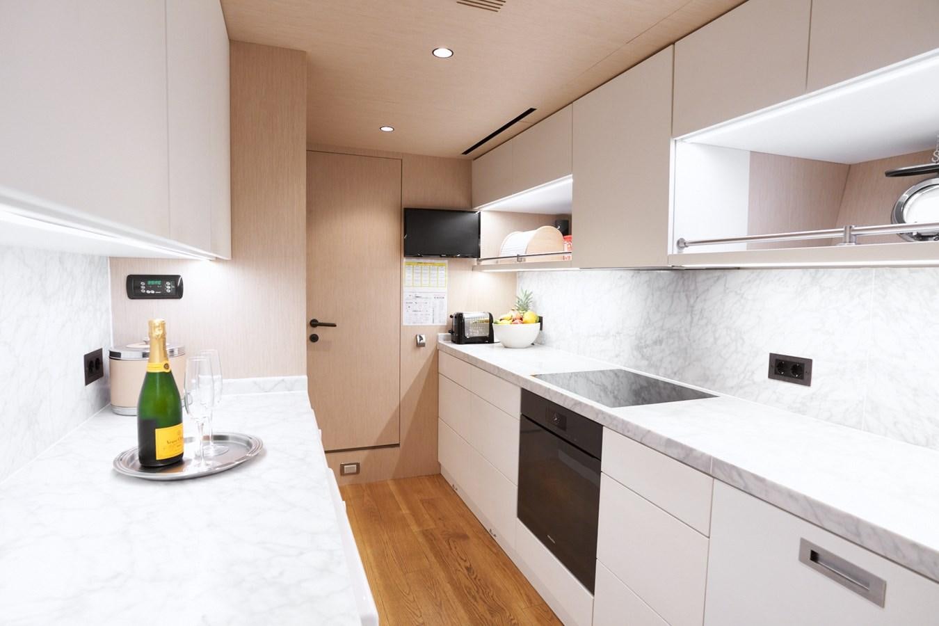 a kitchen with a glass bottle and a glass of wine on a plate aboard MANGUSTA 108 Yacht for Sale