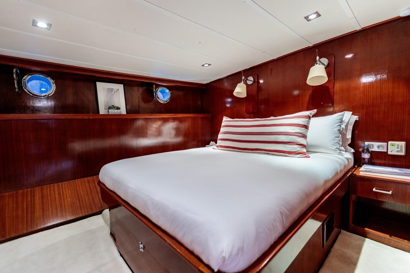 a bed with a white sheet and red pillows aboard VITA DOLCE Yacht for Sale