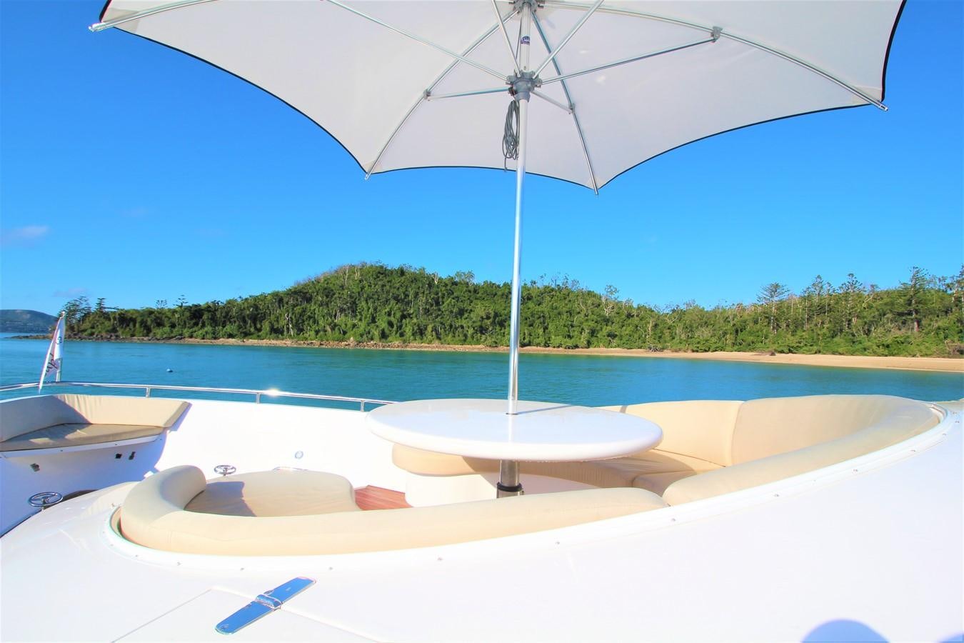 a white umbrella on a white lounge chair on a beach aboard EUPHORIA Yacht for Sale