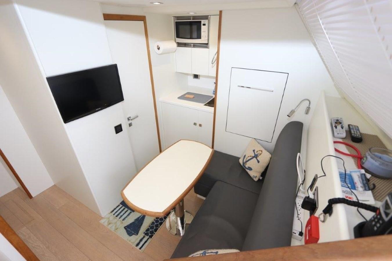a small living room with a small television and a black chair aboard AQUA VISTA Yacht for Sale