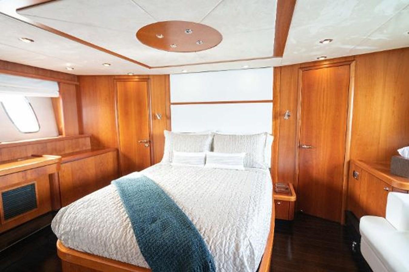 a bedroom with a bed and a wood cabinet aboard SOLE MIO Yacht for Sale