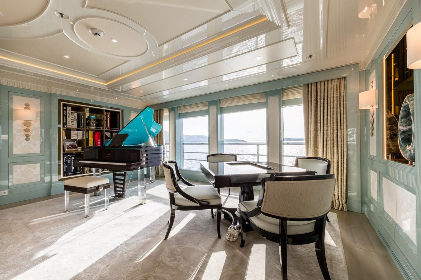 a room with a table chairs and a piano aboard PLVS VLTRA Yacht for Sale